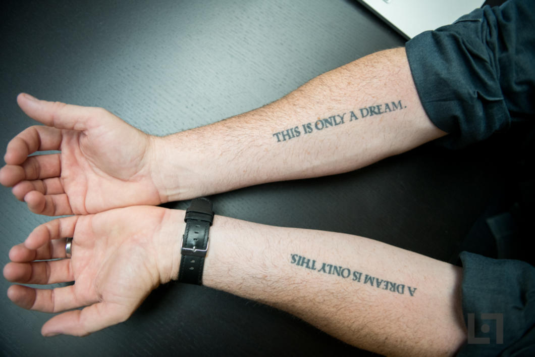photo of mans arms with tattoos saying this is only a dream