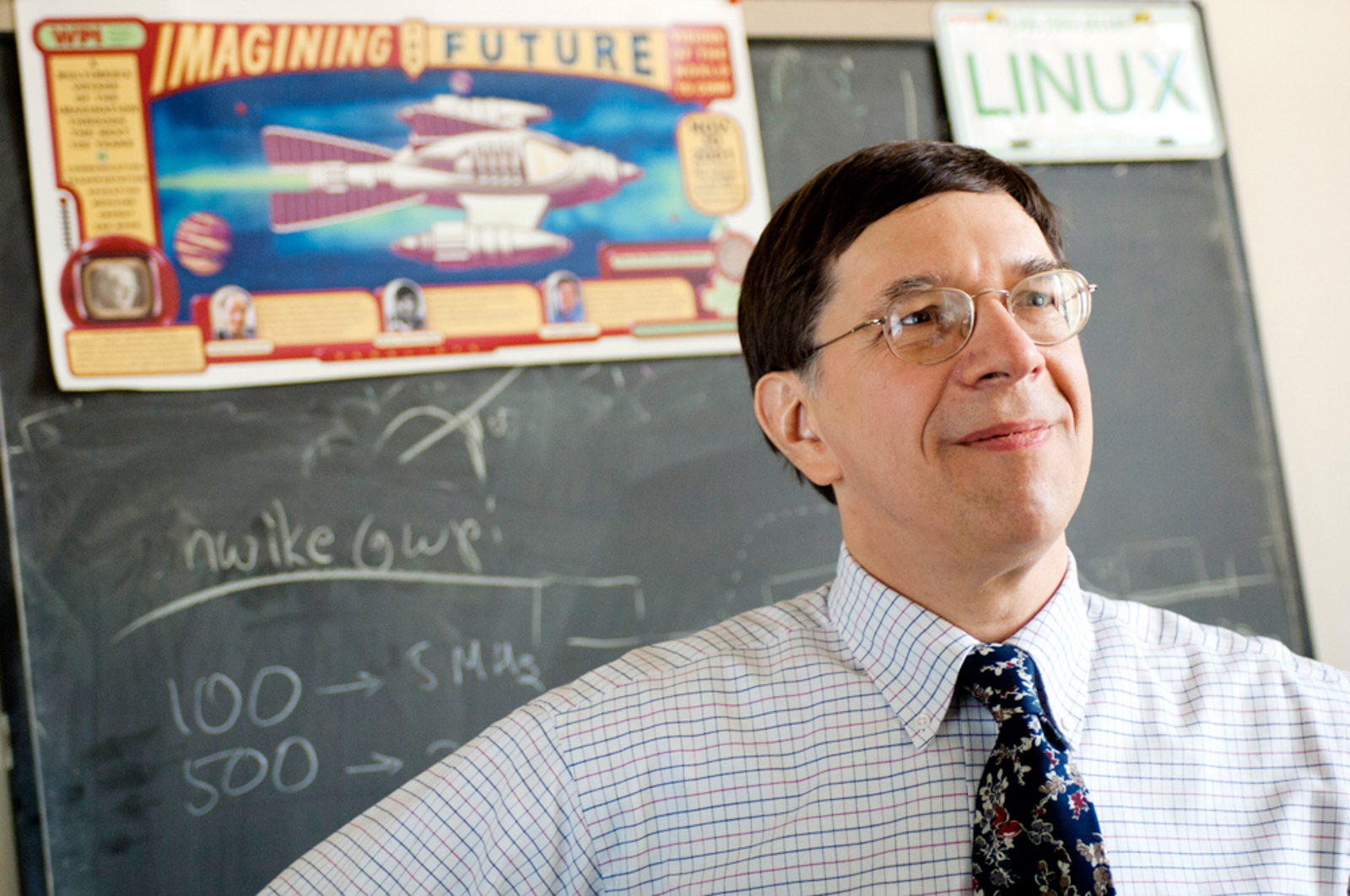 Photo of professor looking off in front of blackboard