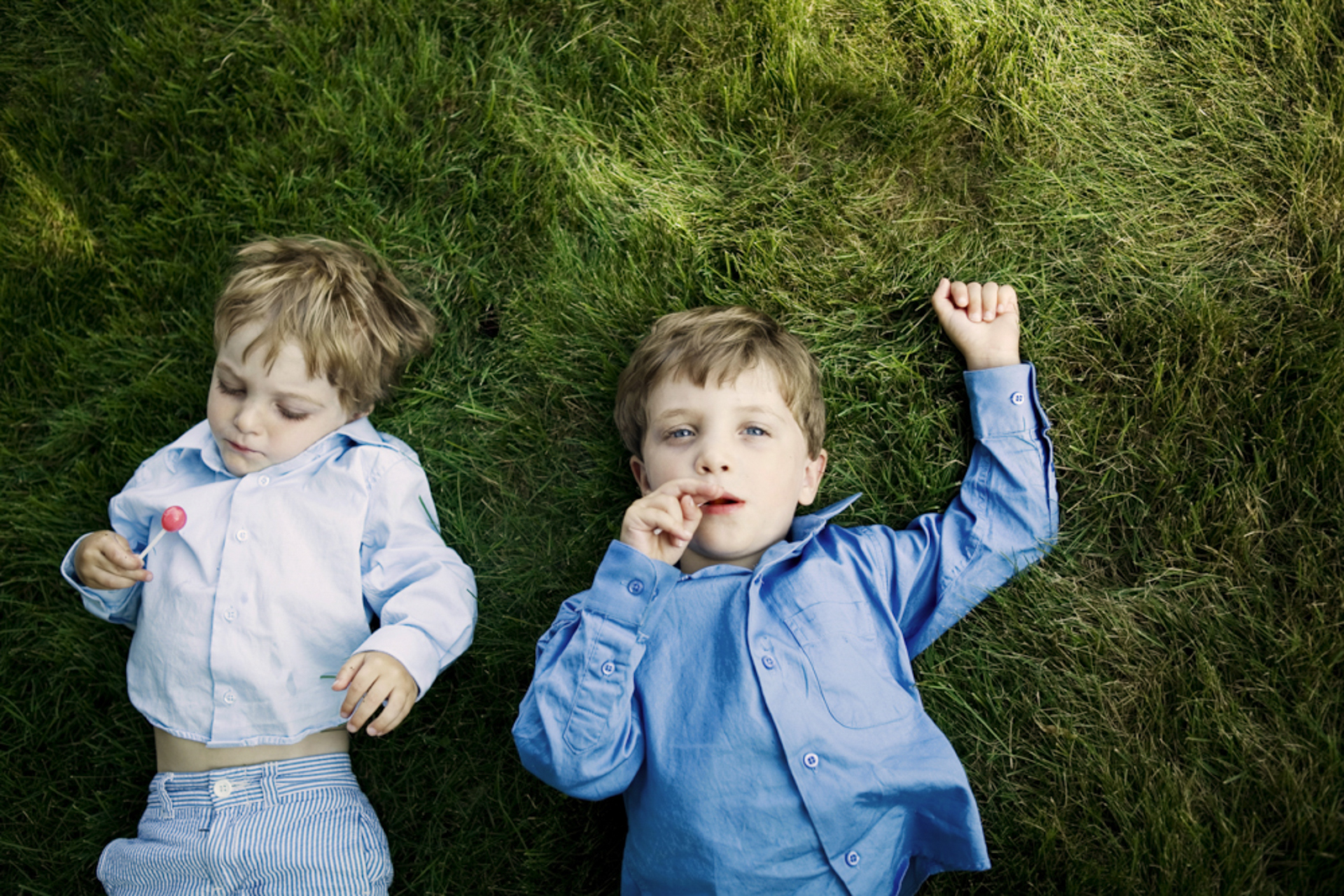 two young boys with lollipops on grass