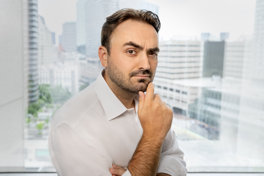 Man in an office with a cheeky expression, raising one eyebrow