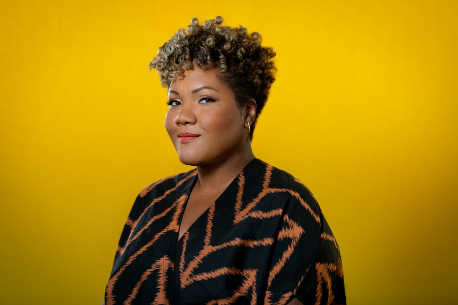 Woman standing in front of yellow background, with a confident expression