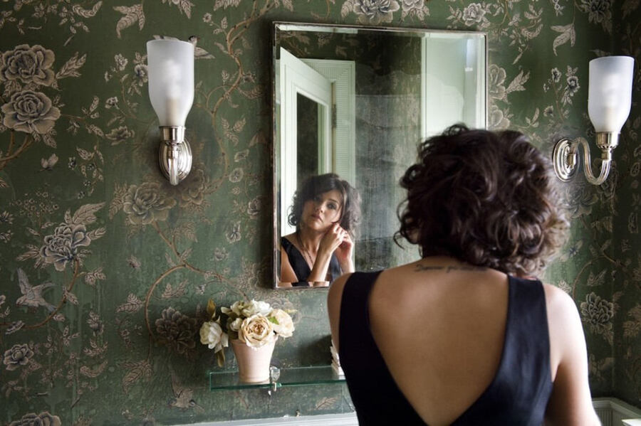 woman putting on earrings in the mirror